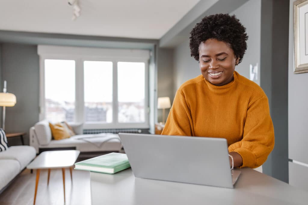 Young smiling African-American woman working on laptop
