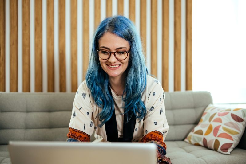 woman community manager with blue hair working on community management strategies on laptop