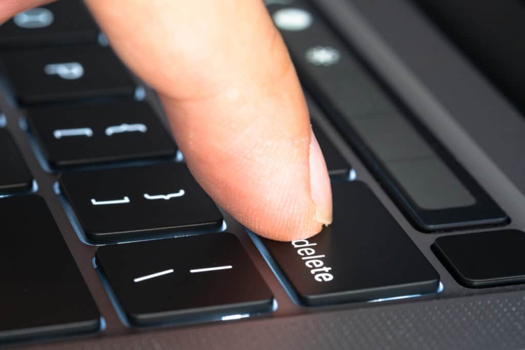 Finger of the computer user, he presses the delete button on the computer keyboard